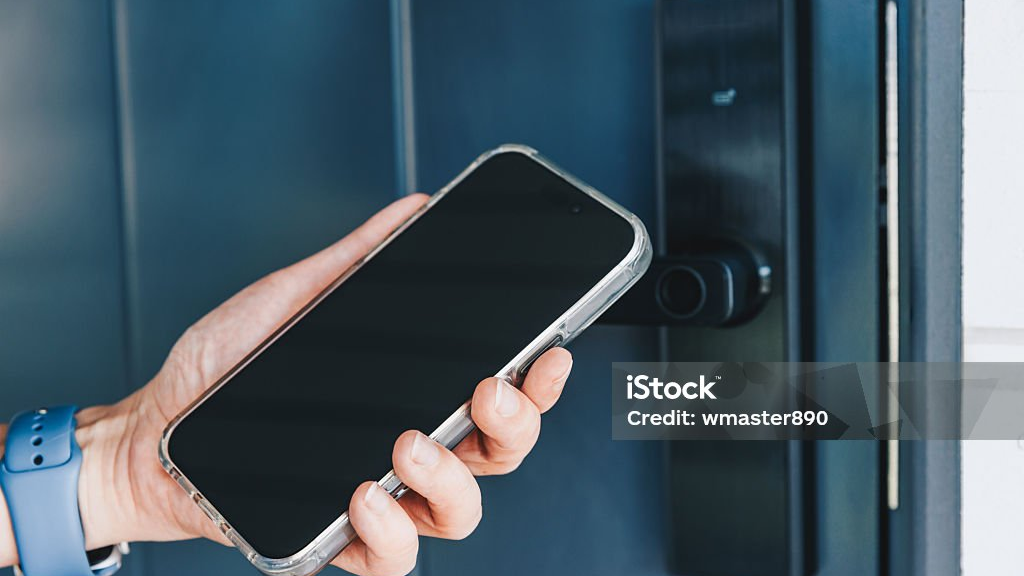 Hand hält ein Handy vor ein elektronisches Türschloss